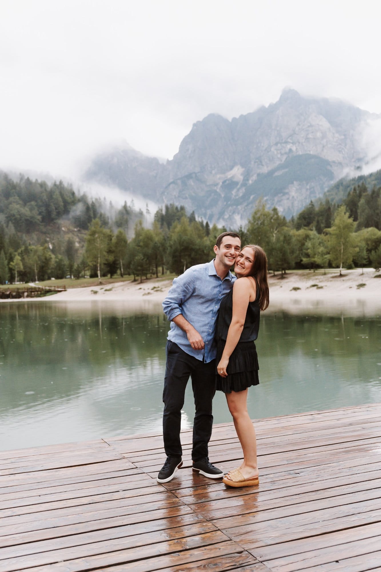 Natural portrait of a newly engaged couple at Lake Jasna with misty mountains behind them