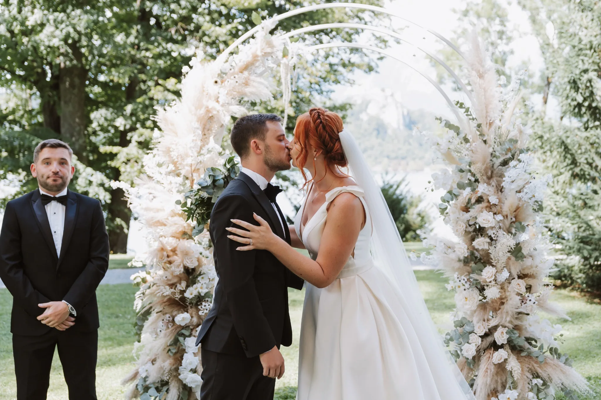 Newlyweds kissing beneath a floral wedding arch at Vila Bled
