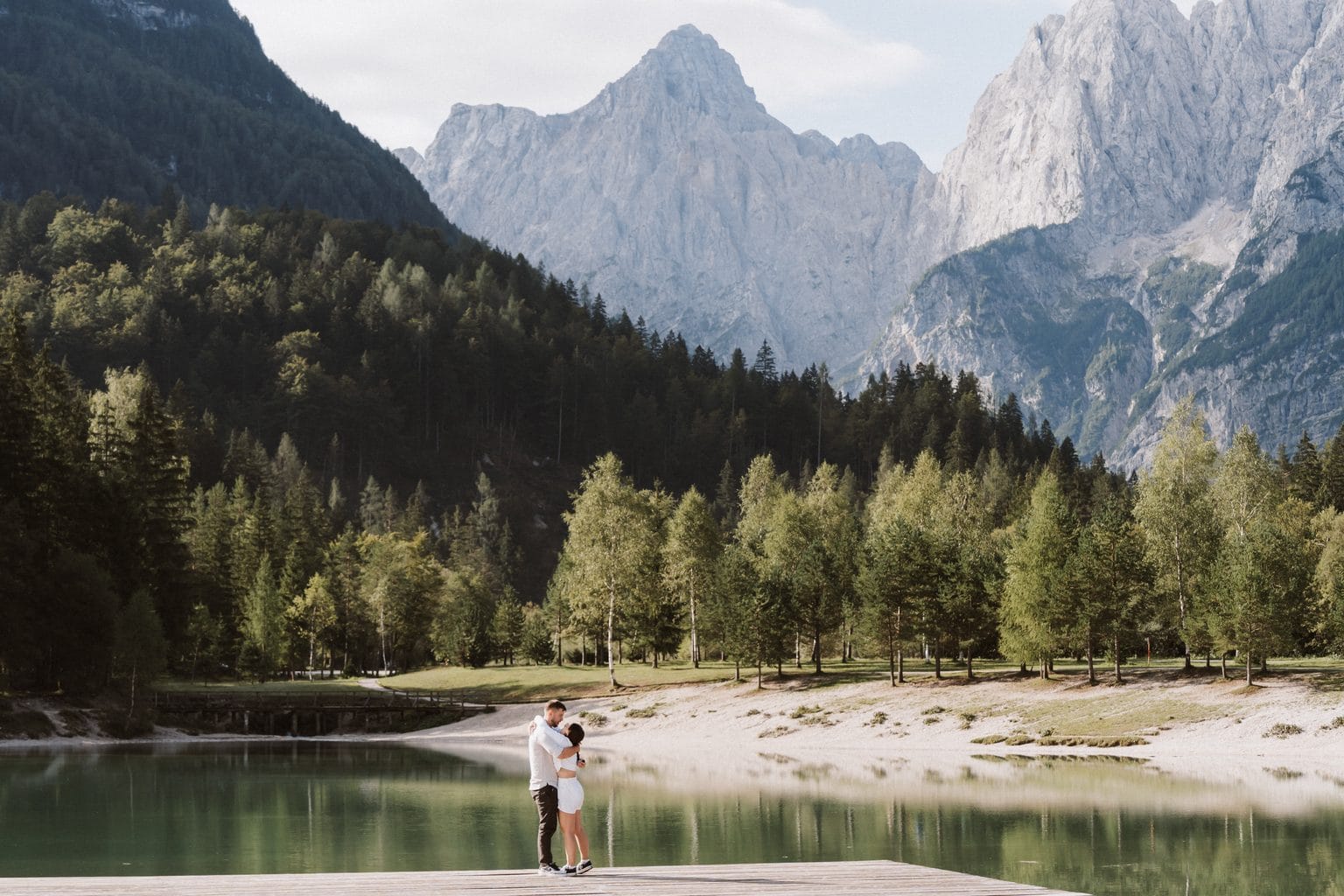 Couple embracing beside Lake Jasna beneath the Julian Alps