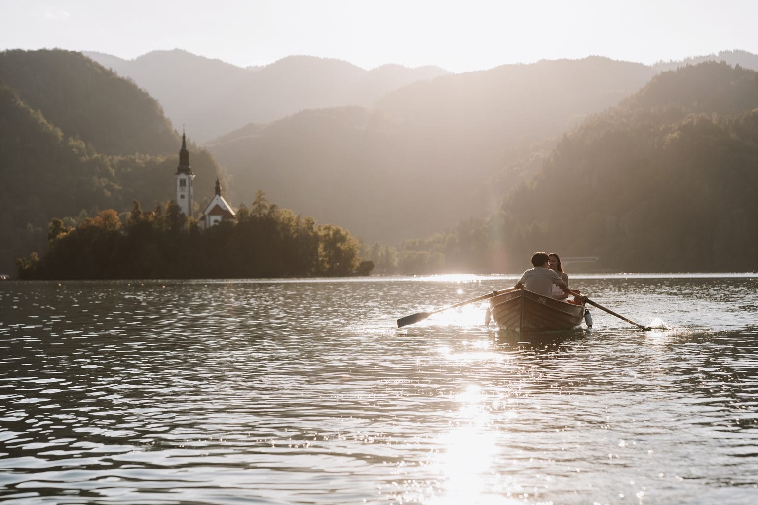Couple in a rowing boat on Lake Bled in golden evening light