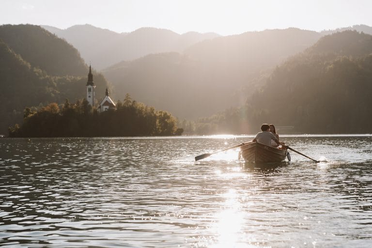 Couple in a rowing boat on Lake Bled in golden evening light