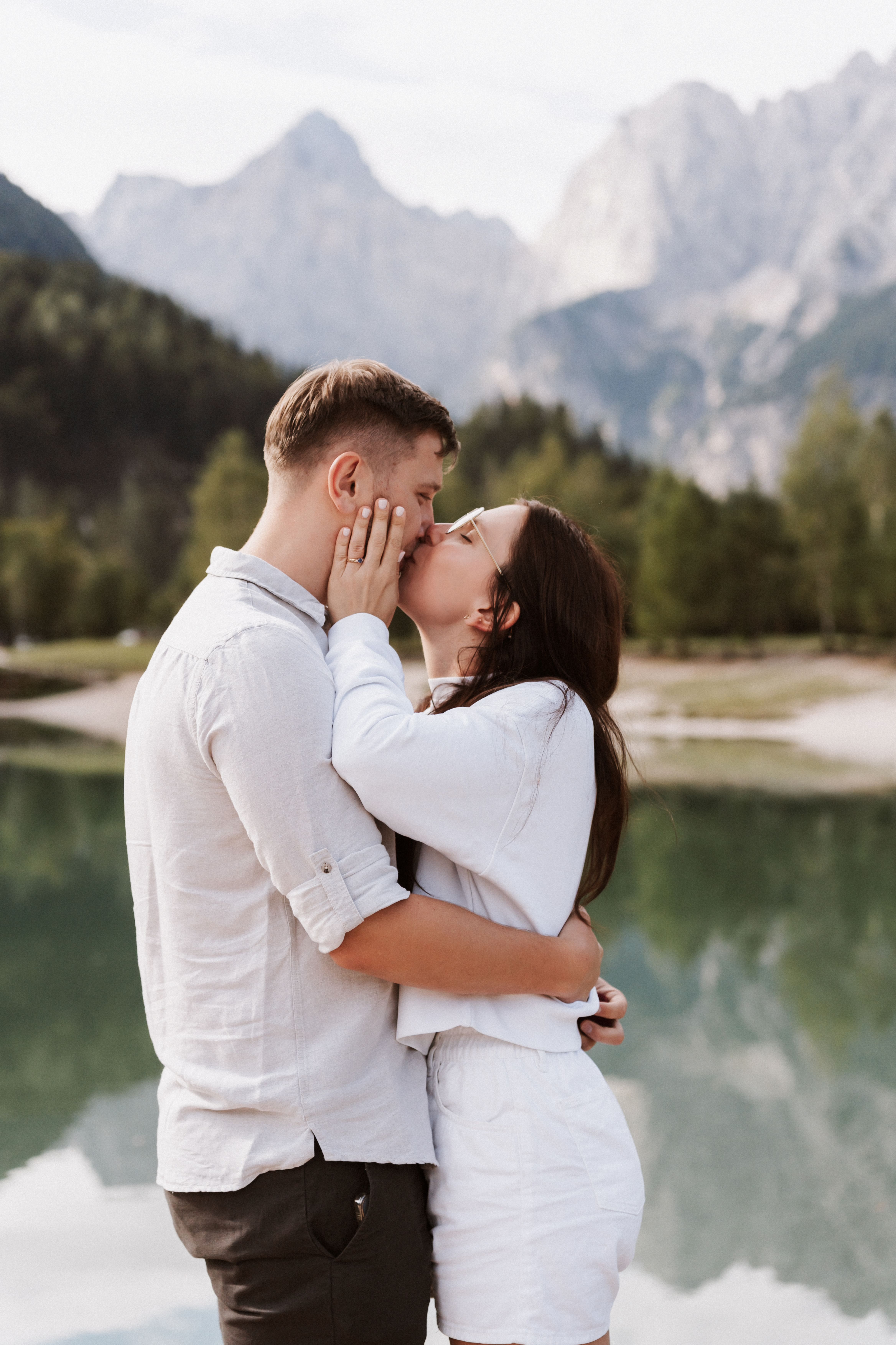 Newly engaged couple kissing at Lake Jasna with the Julian Alps behind them